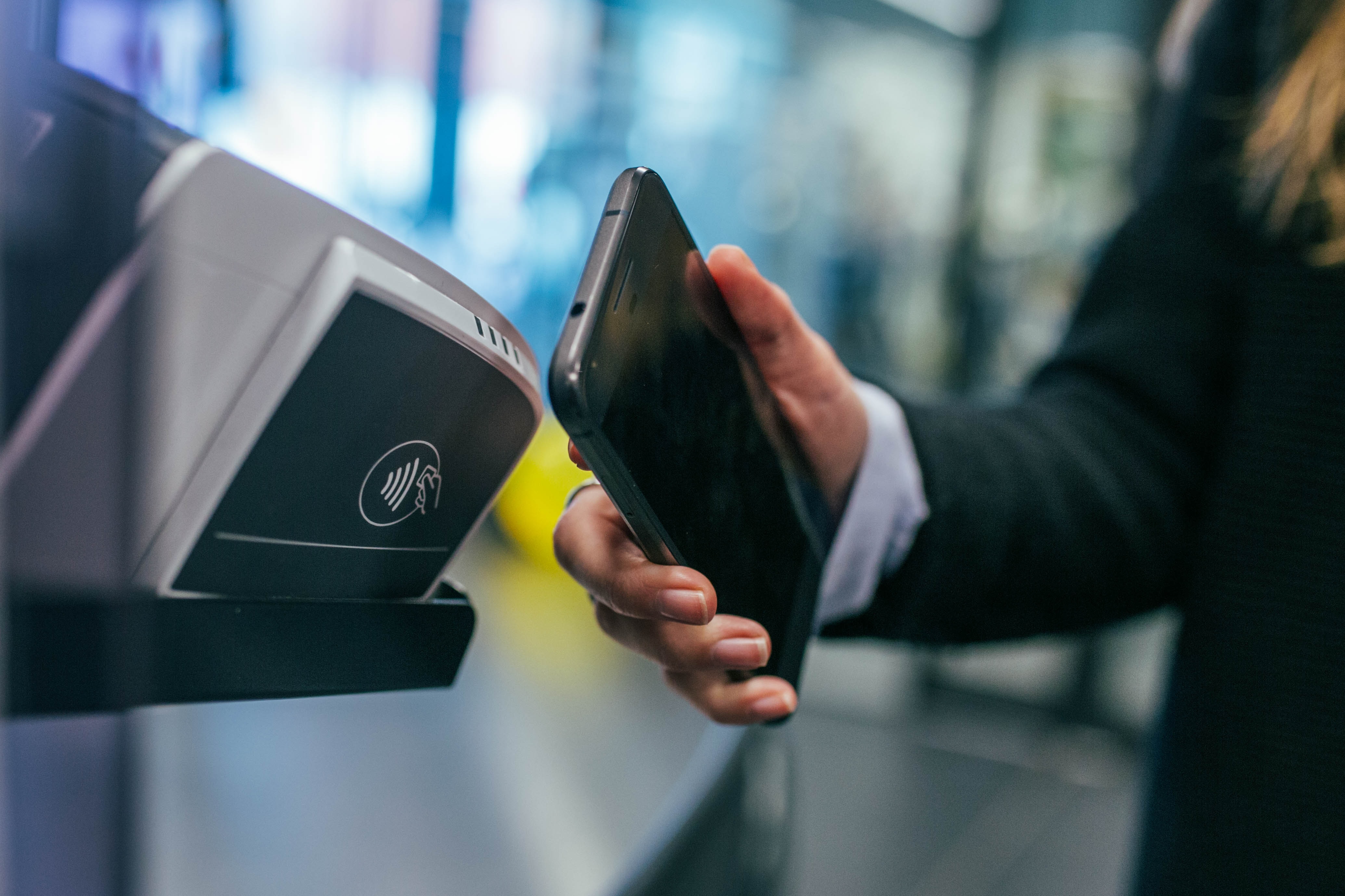 Someone making a digital payment with a phone against a reader