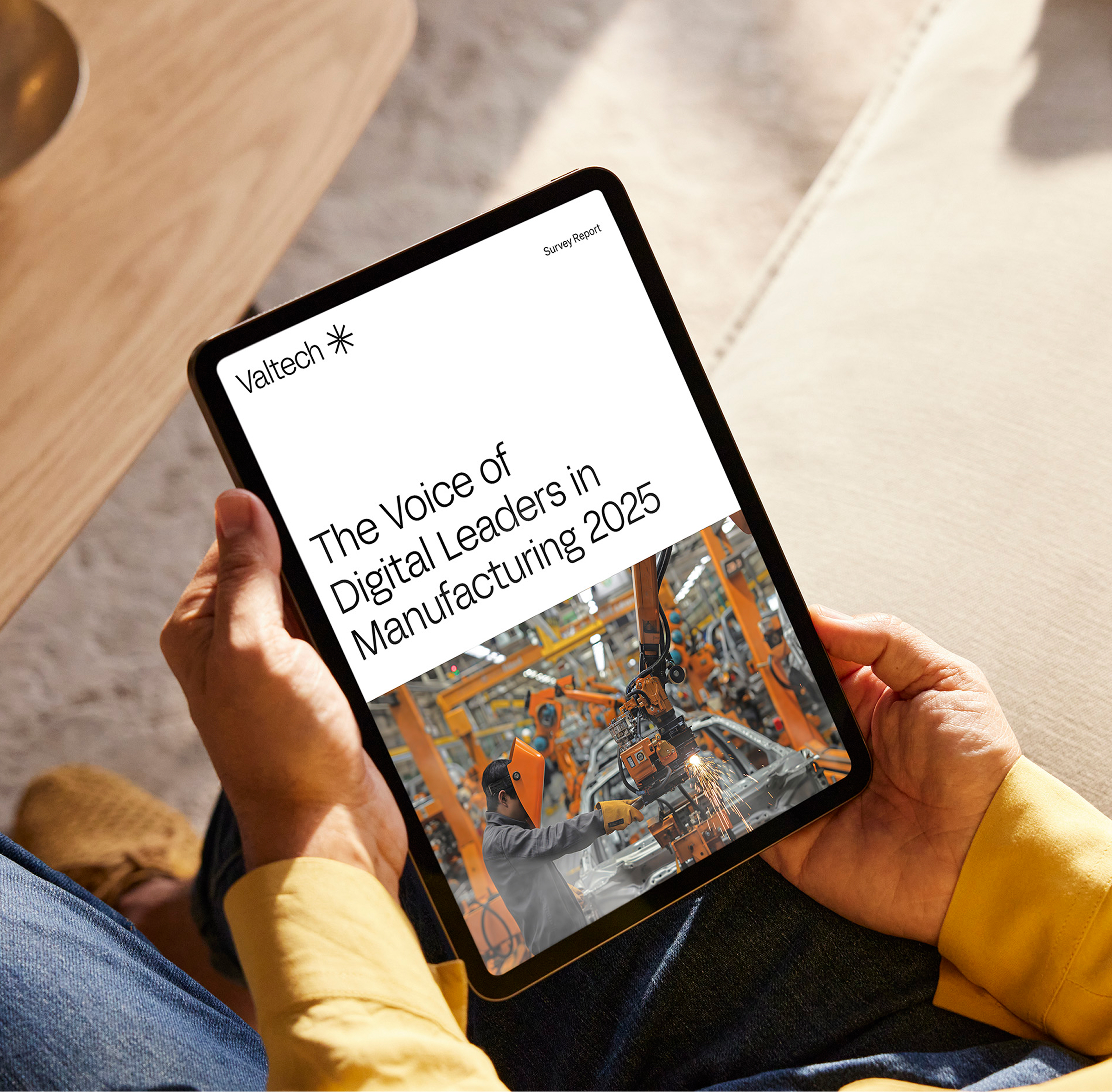 Person viewing Valtech survey report, The Voice of Digital Leaders in Manufacturing 2025, on tablet.