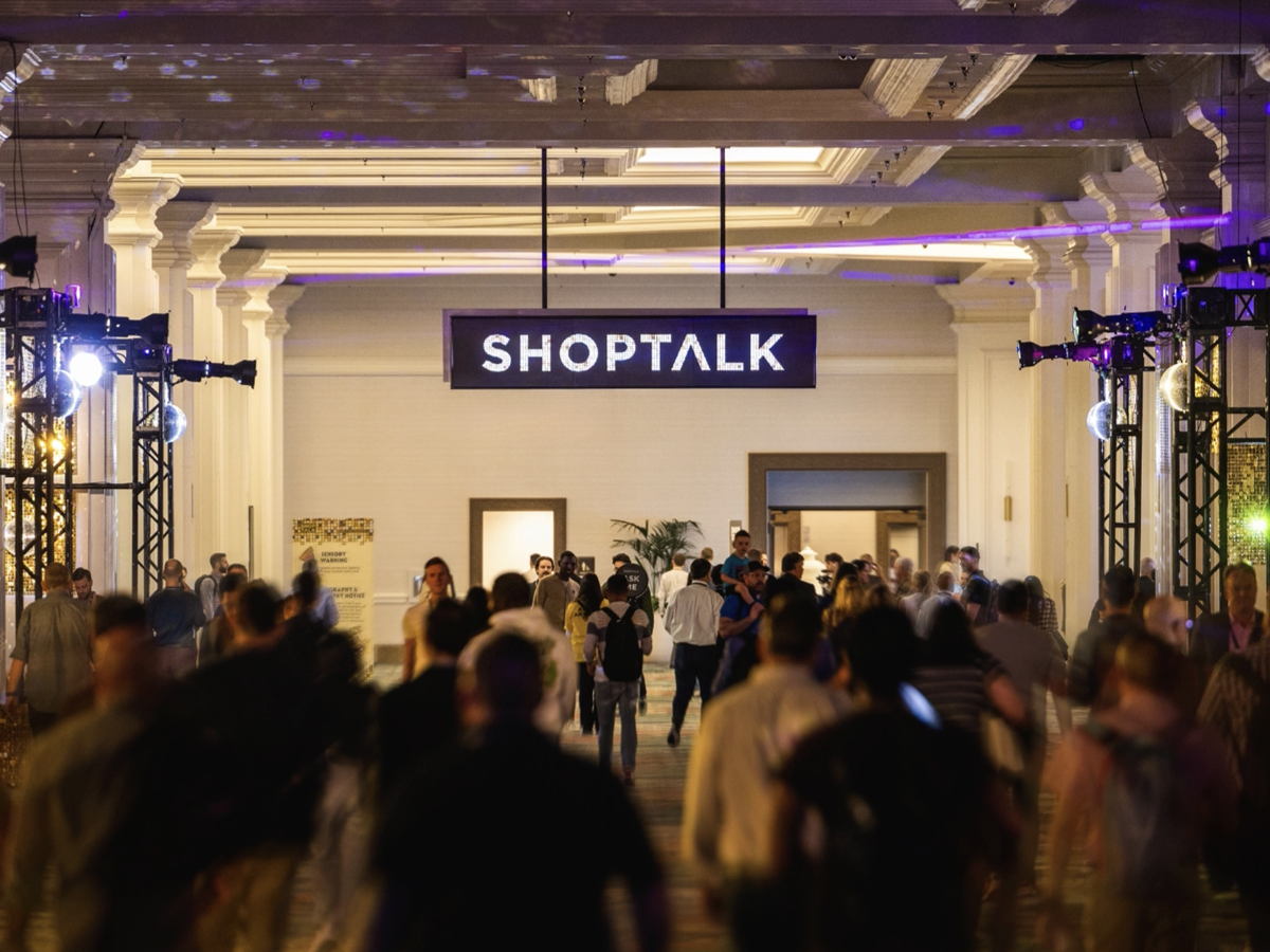 Crowd of attendees entering the Shoptalk conference hall under an illuminated Shoptalk sign.